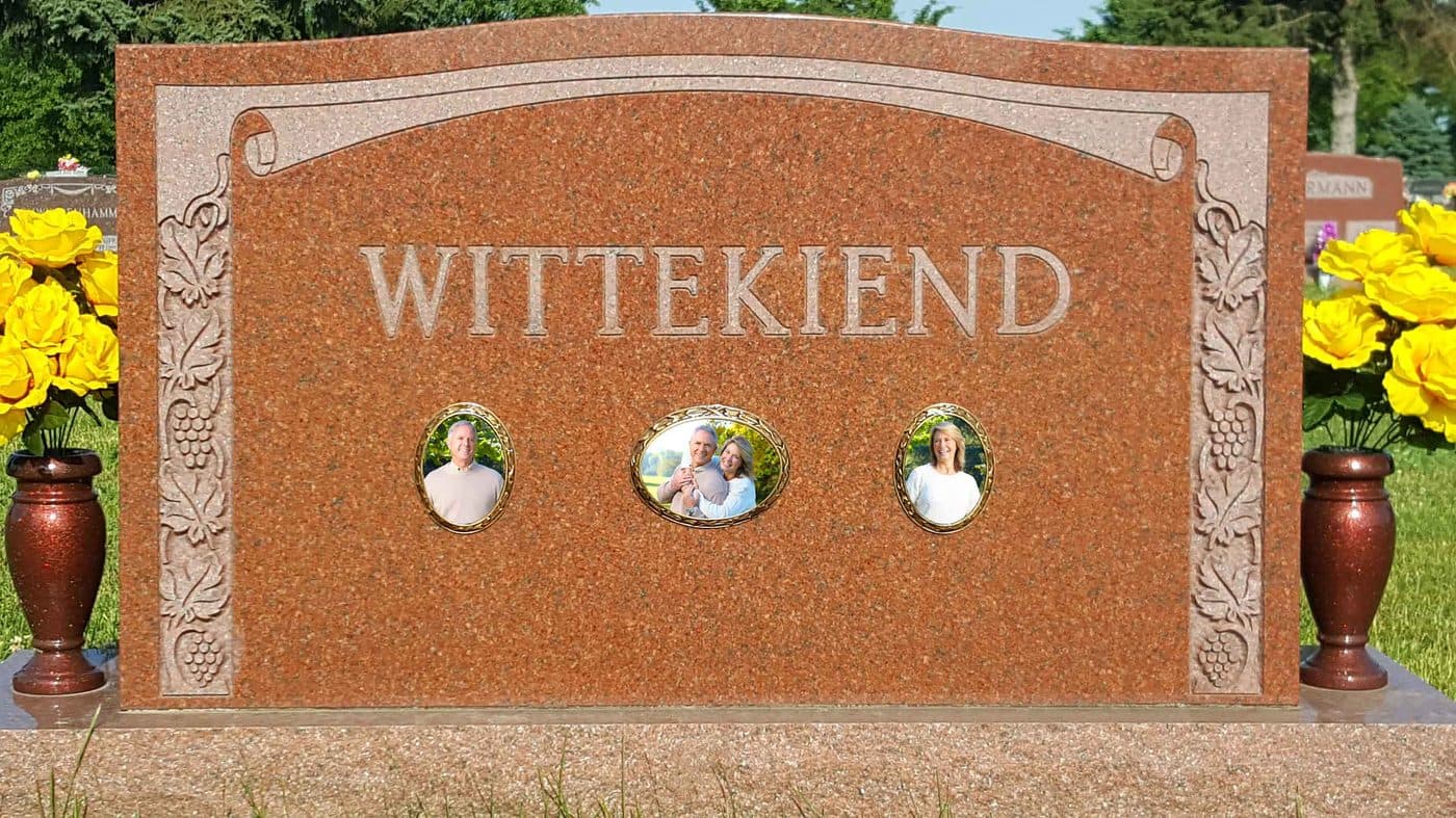 A granite headstone with three oval ceramic photos of a family